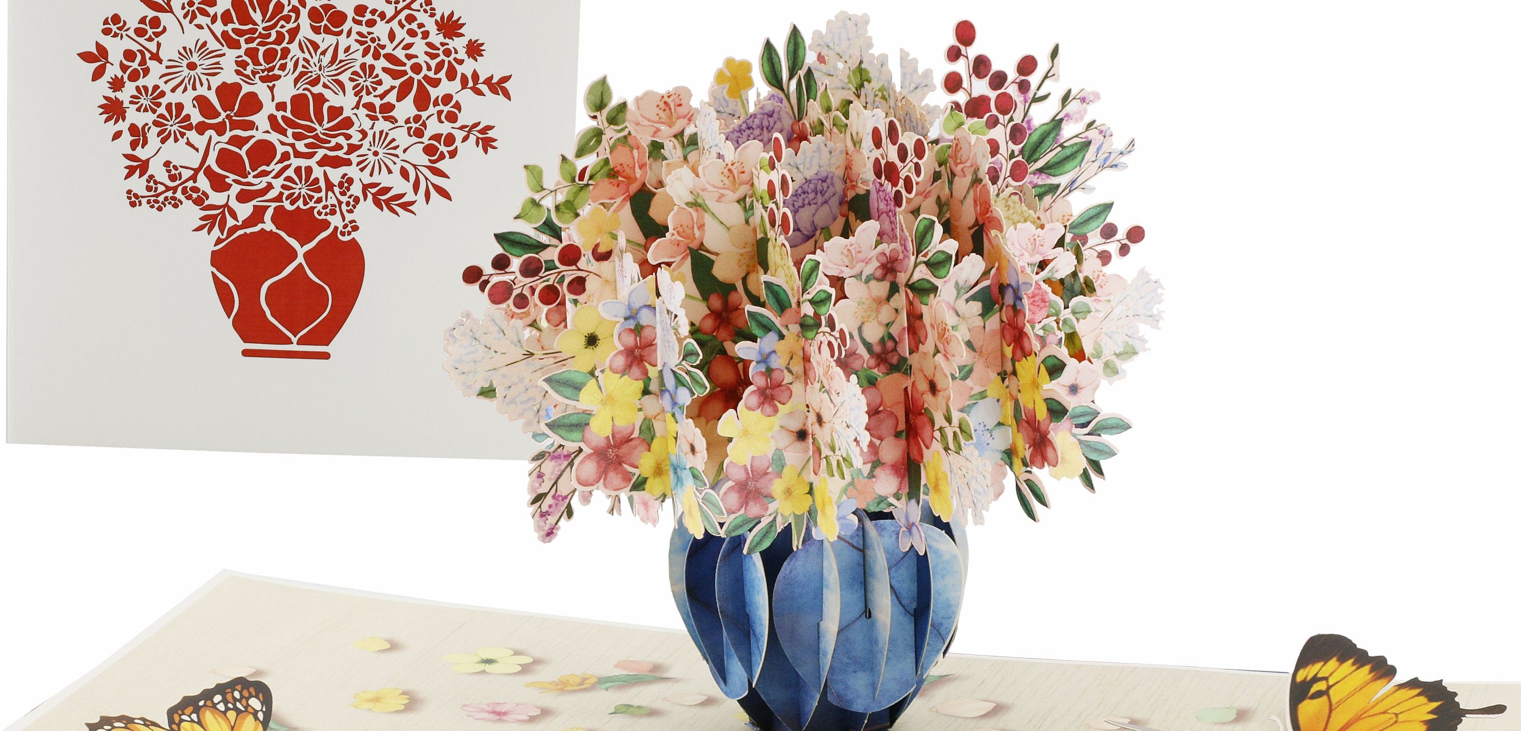 Aufgeklappte Pop-up-Karte mit einem bunten Blumenstrauß in blauer Vase und Schmetterlingen, daneben die weiße Kartenvorderseite mit Blumenstrauß-Scherenschnitt.