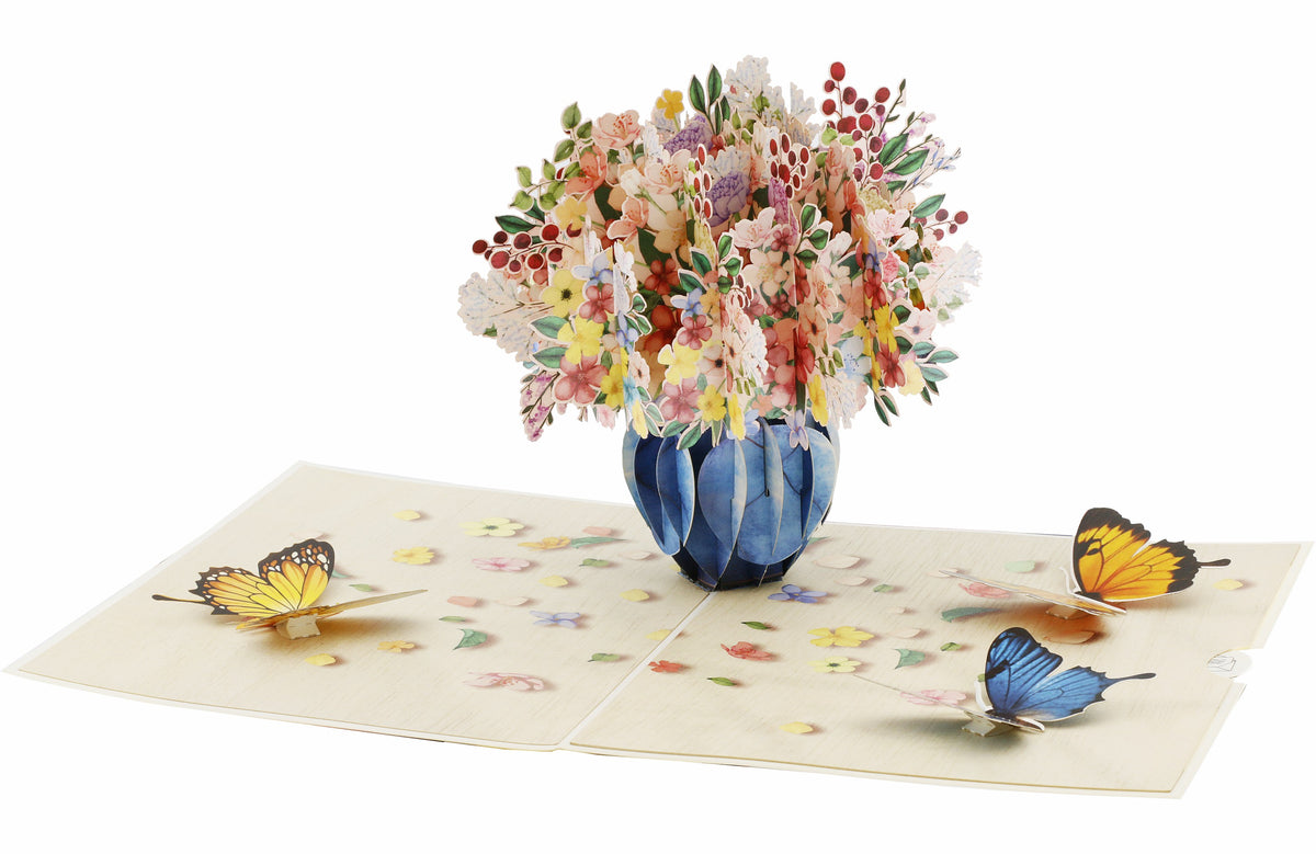 Aufgeklappte Pop-up-Karte mit Blumenstrauß und Schmetterlingen, schräg von oben fotografiert.