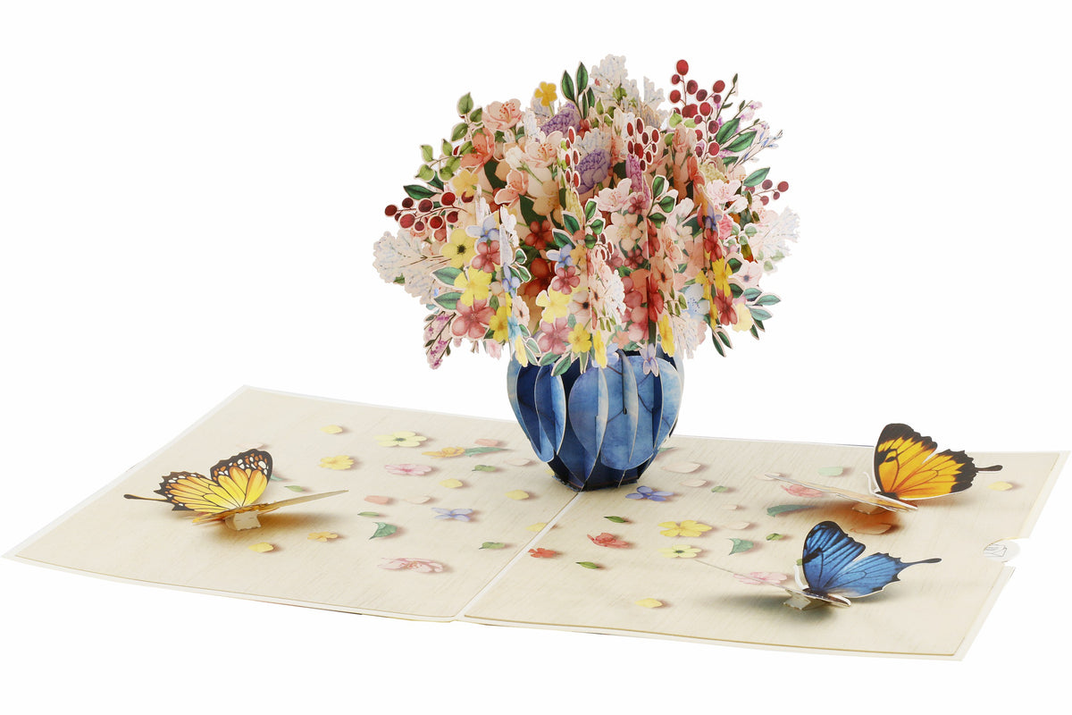 Aufgeklappte Pop-up-Karte mit Blumenstrauß und Schmetterlingen, schräg von oben fotografiert.