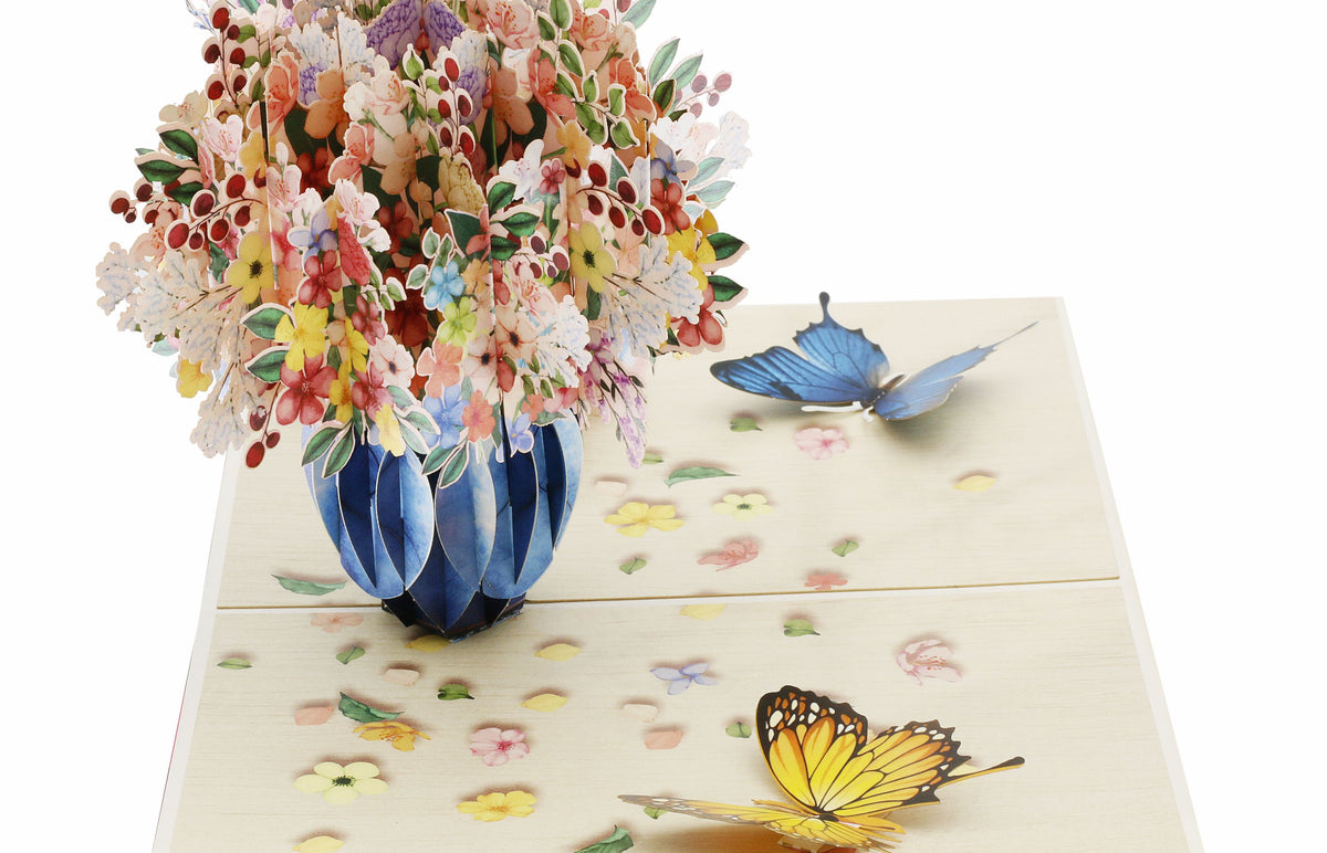 Nahaufnahme der aufgeklappten Pop-up-Karte mit üppigem Blumenstrauß in blauer Vase.