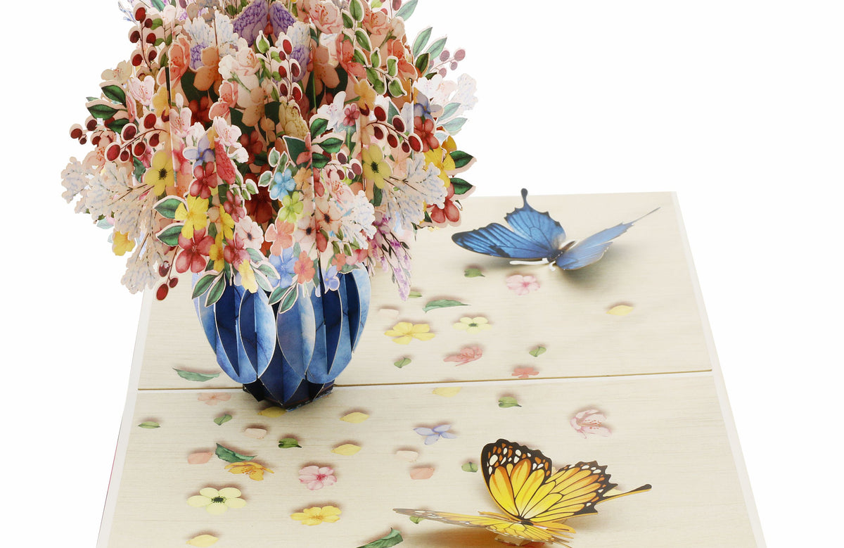 Nahaufnahme der aufgeklappten Pop-up-Karte mit üppigem Blumenstrauß in blauer Vase.