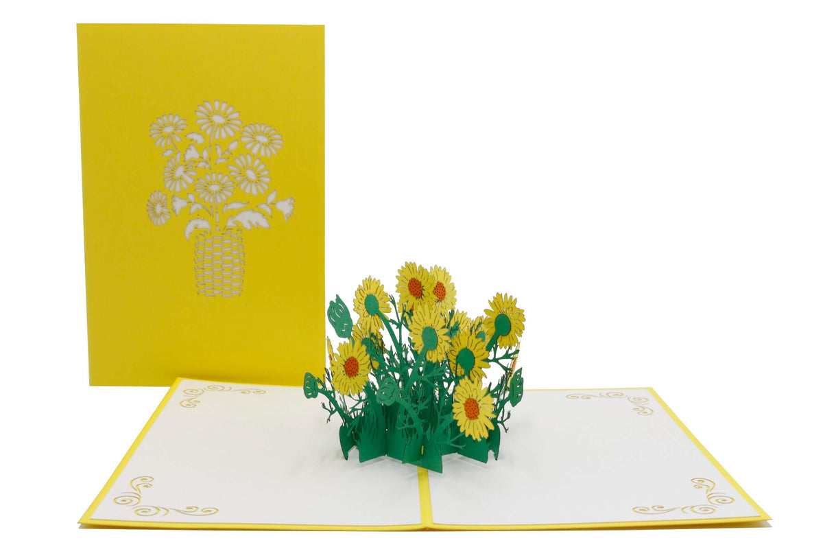 Aufgeklappte Pop-up-Karte mit gelben Gänseblümchen, daneben die gelbe Kartenvorderseite mit Blumen-Scherenschnitt.