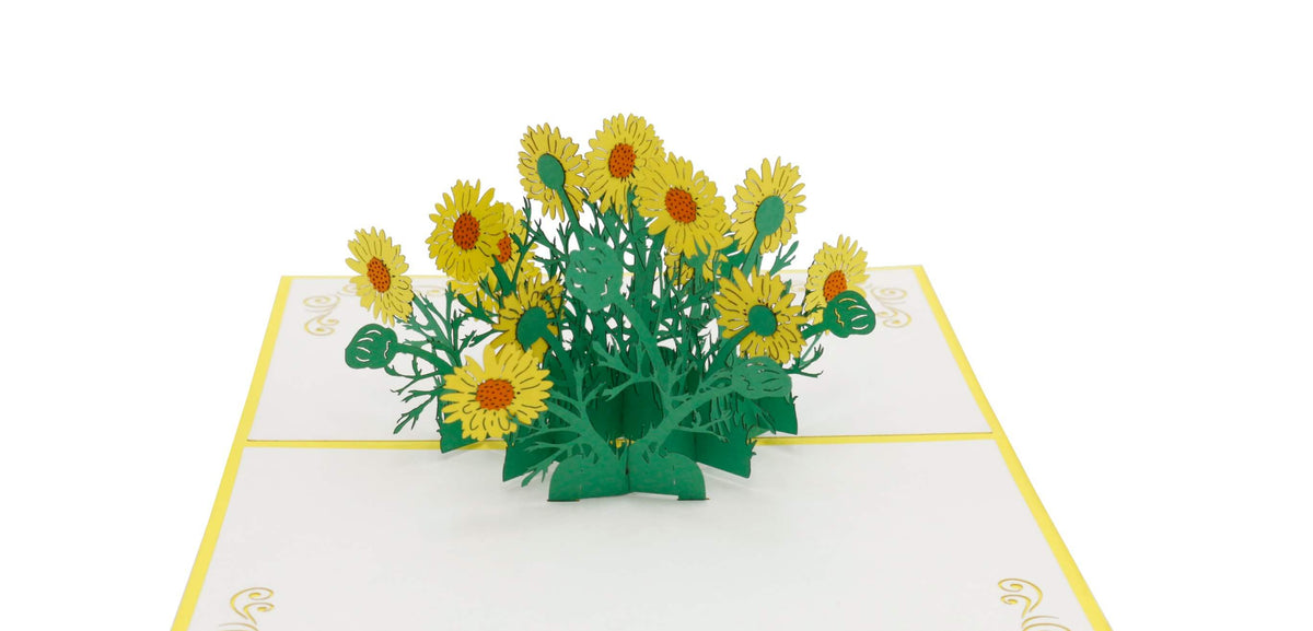 Aufgeklappte Pop-up-Karte mit gelben Gänseblümchen aus Papier, schräg von der Seite fotografiert.