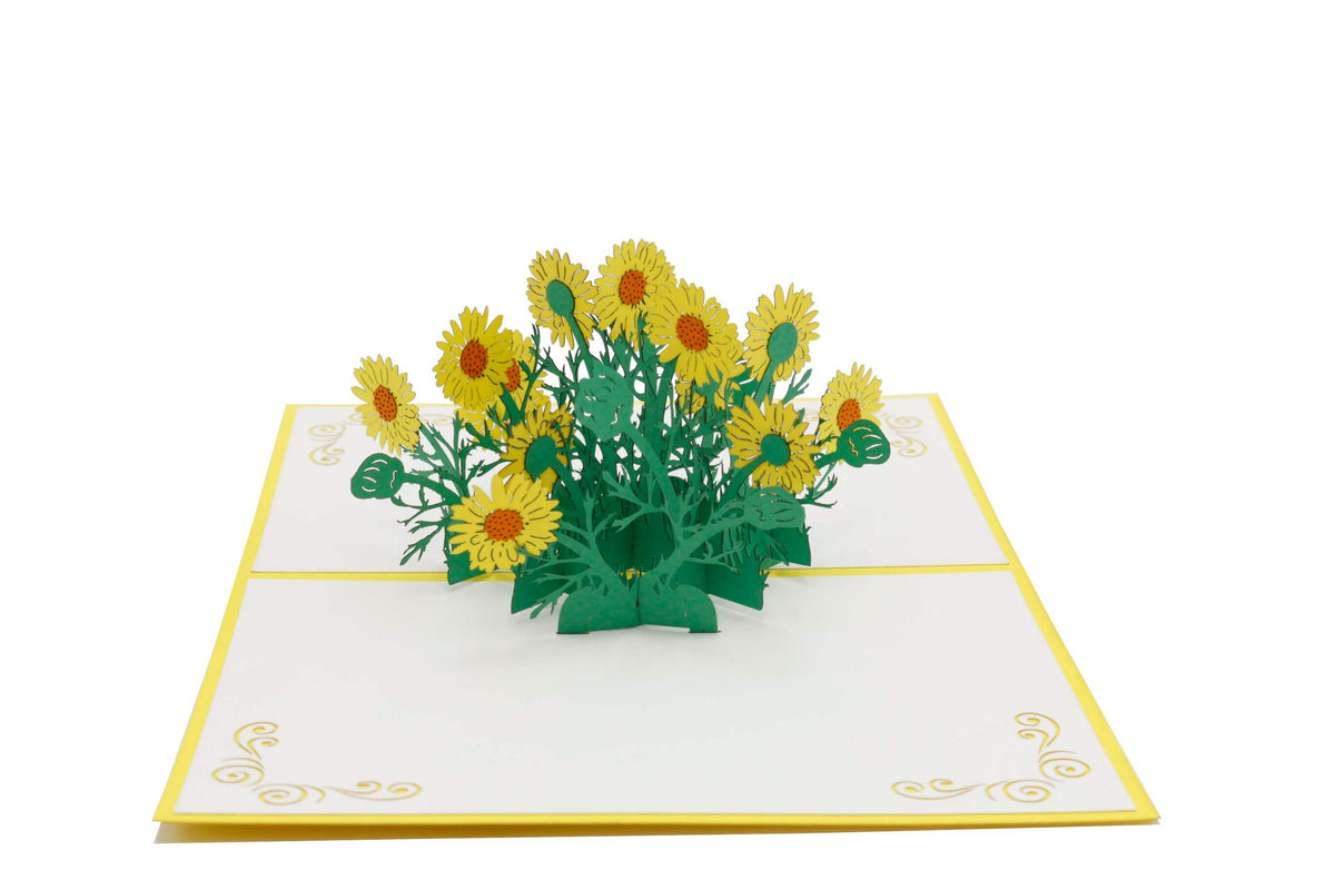 Aufgeklappte Pop-up-Karte mit gelben Gänseblümchen aus Papier, schräg von der Seite fotografiert.