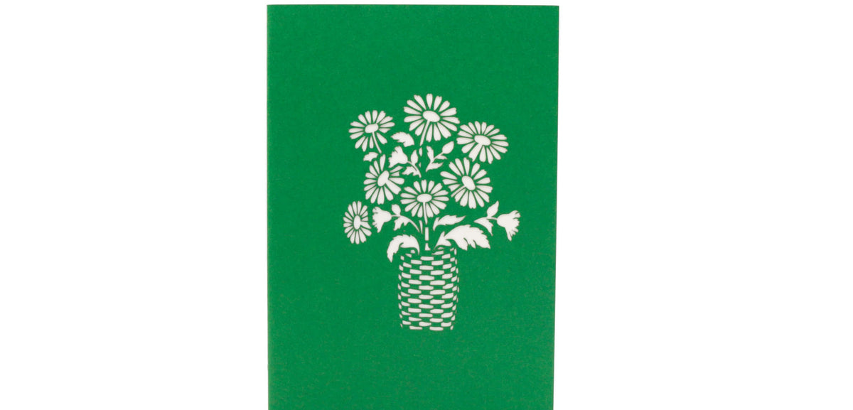 Grüne Kartenvorderseite mit einem Blumenstrauß im Korb als Scherenschnitt.