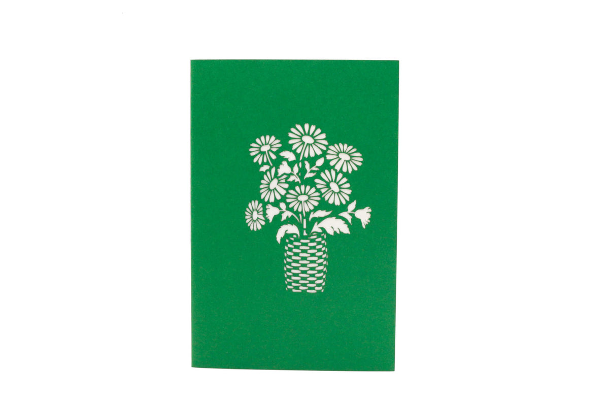 Grüne Kartenvorderseite mit einem Blumenstrauß im Korb als Scherenschnitt.