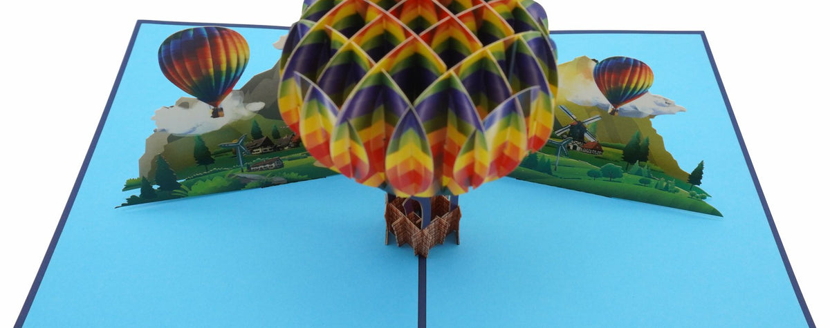 Nahaufnahme der aufgeklappten Pop-up-Karte mit buntem Heißluftballon über Bergen und Wolken.