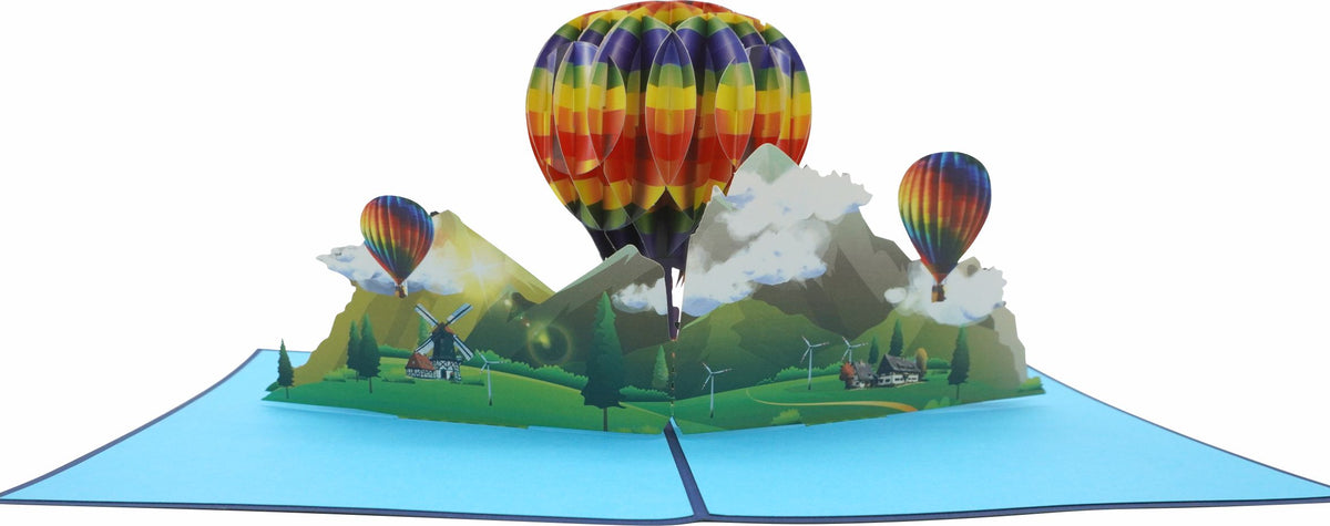 Aufgeklappte Pop-up-Karte mit drei Heißluftballons über einer Landschaft, frontal fotografiert.