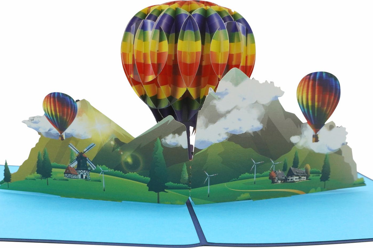 Aufgeklappte Pop-up-Karte mit drei Heißluftballons über einer Landschaft, frontal fotografiert.