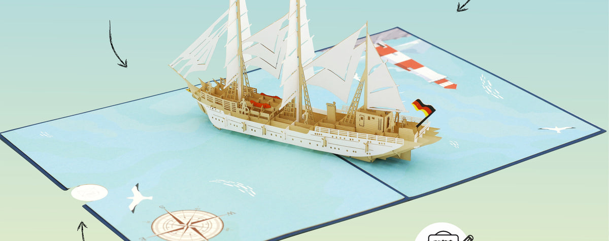 Geöffnete Pop-up-Karte mit einem aufklappbaren Gorch Fock Segelschiff in der Mitte, Kompassrose und Möwe auf der Kartenfläche.