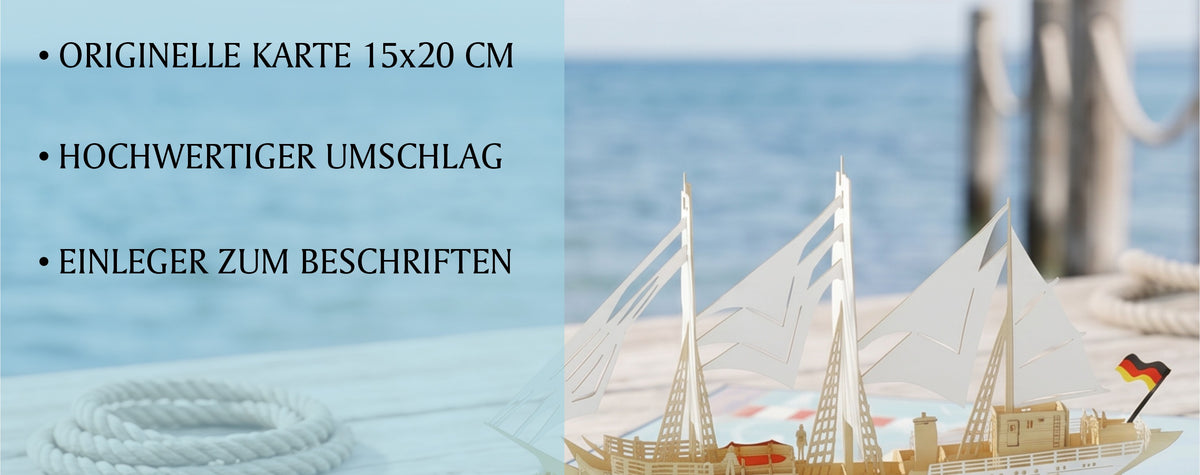 Geöffnete Pop-up-Karte mit einem aufklappbaren Gorch Fock Segelschiff in der Mitte, Kompassrose und Leuchtturm auf der Kartenfläche. Im Hintergrund ein Steg am Meer.