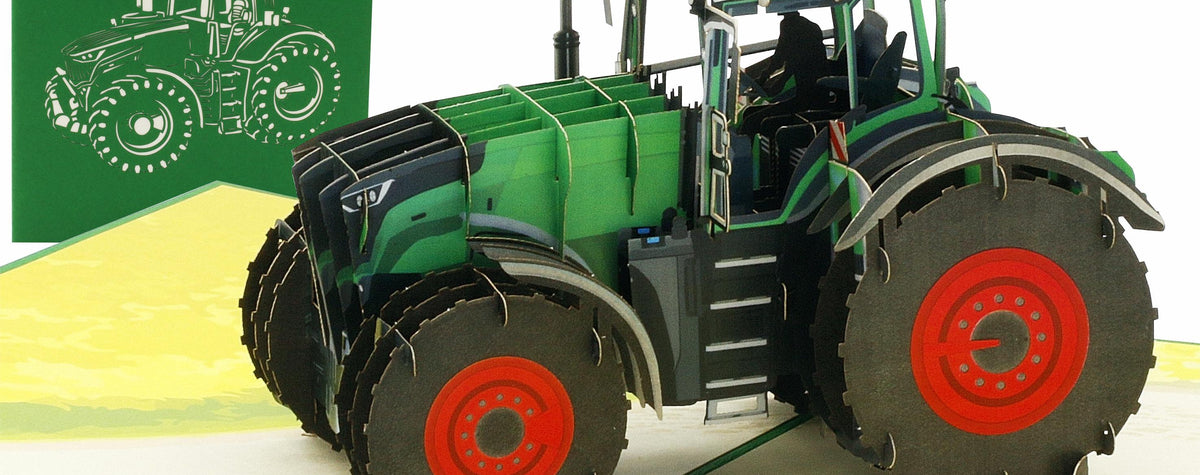 Aufgeklappte Pop-up-Karte mit einem grünen Traktor mit roten Felgen auf einem Feld, dahinter die grüne Kartenvorderseite mit Traktor-Scherenschnitt.