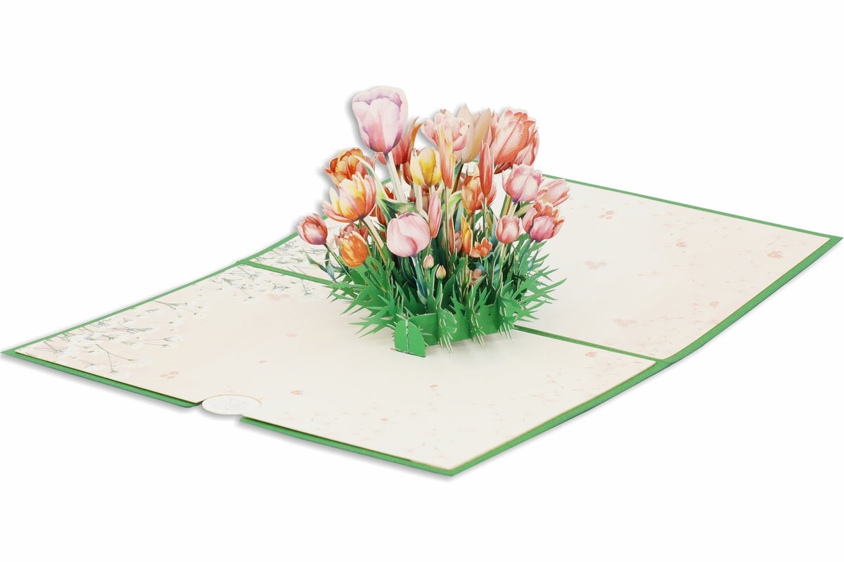 Aufgeklappte Pop-up-Karte mit rosa und orangefarbenen Tulpen aus Papier, frontal fotografiert.