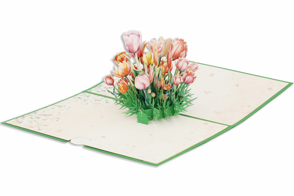 Aufgeklappte Pop-up-Karte mit rosa und orangefarbenen Tulpen aus Papier, frontal fotografiert.