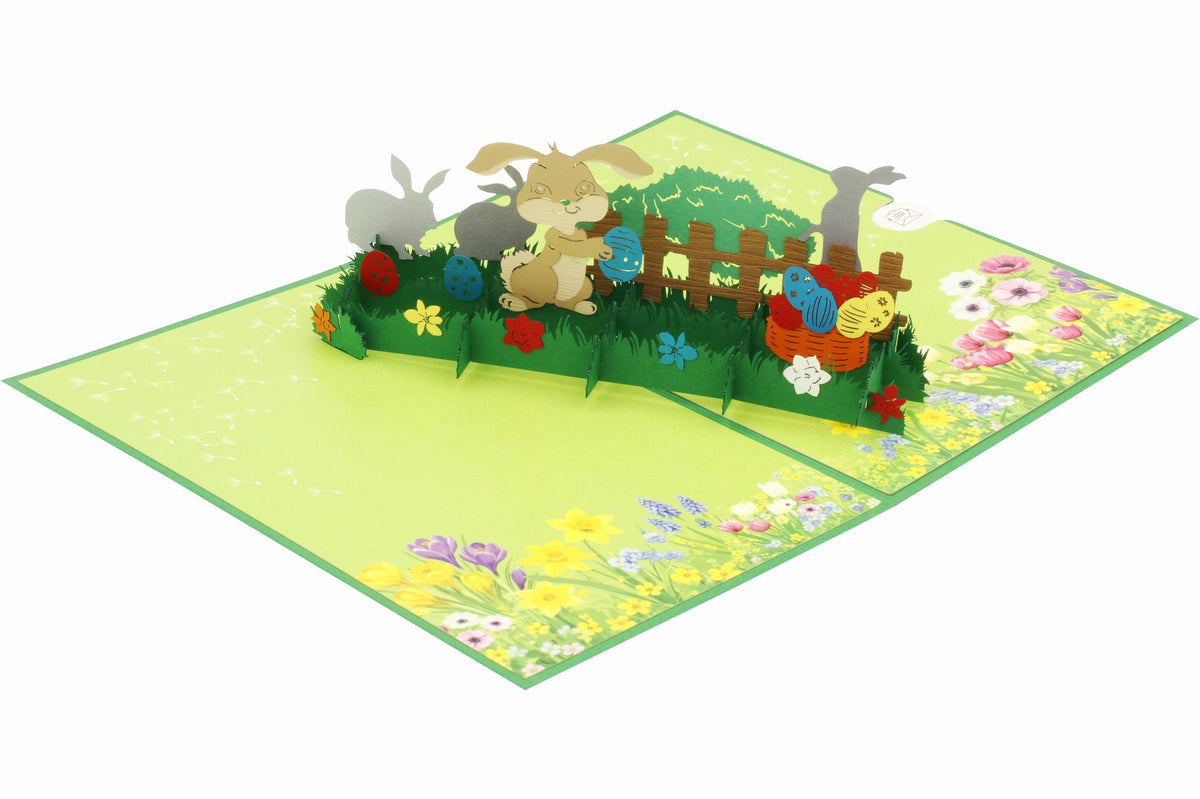 Aufgeklappte Pop-up-Karte mit Osterhasen im Garten, von schräg oben fotografiert.