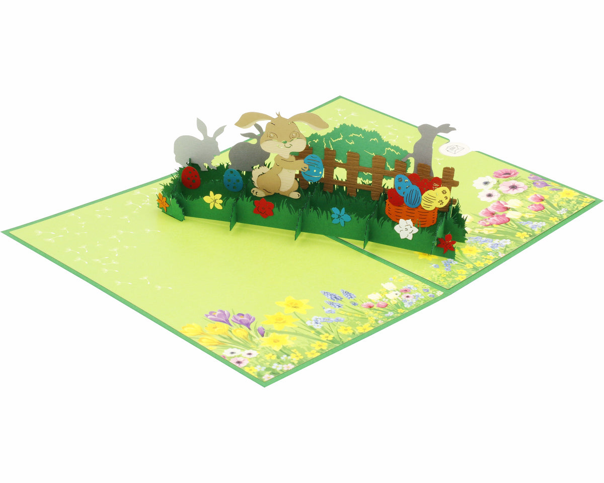 Aufgeklappte Pop-up-Karte mit Osterhasen im Garten, von schräg oben fotografiert.