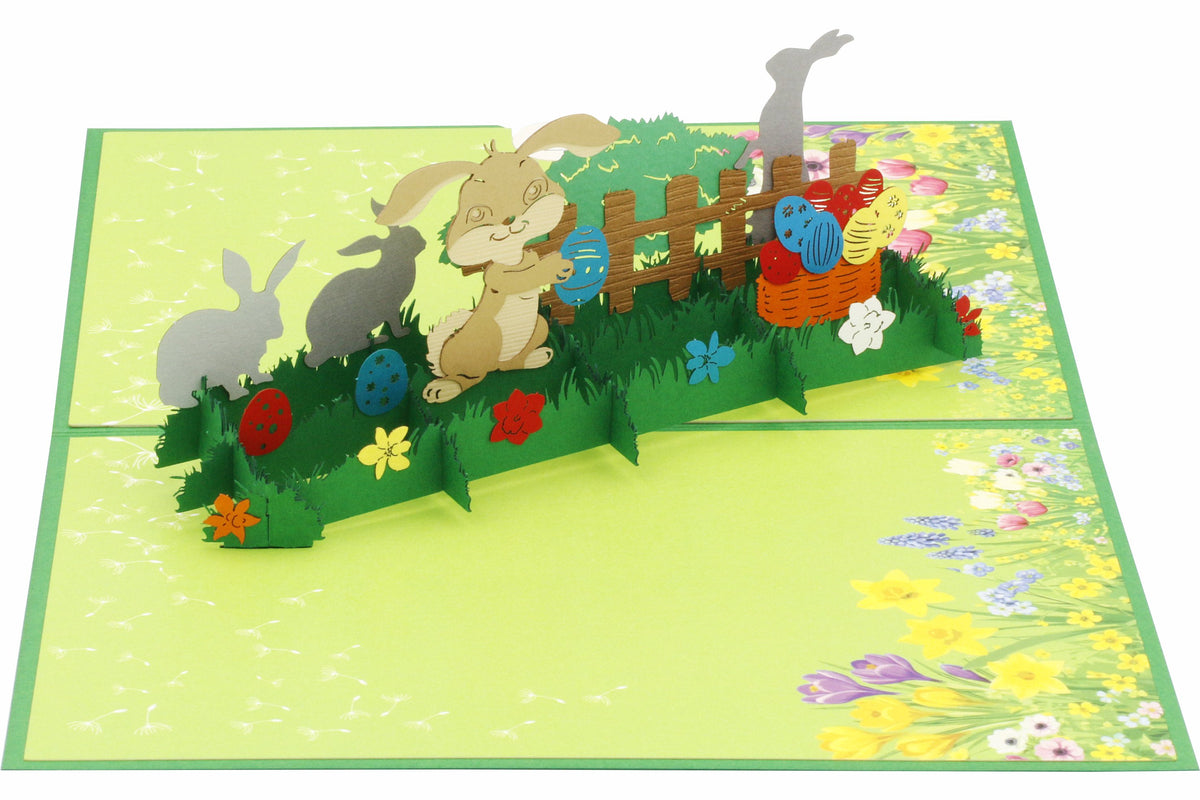 Aufgeklappte Pop-up-Karte mit Osterhasen, bunten Ostereiern und Blumen, schräg von der Seite fotografiert.
