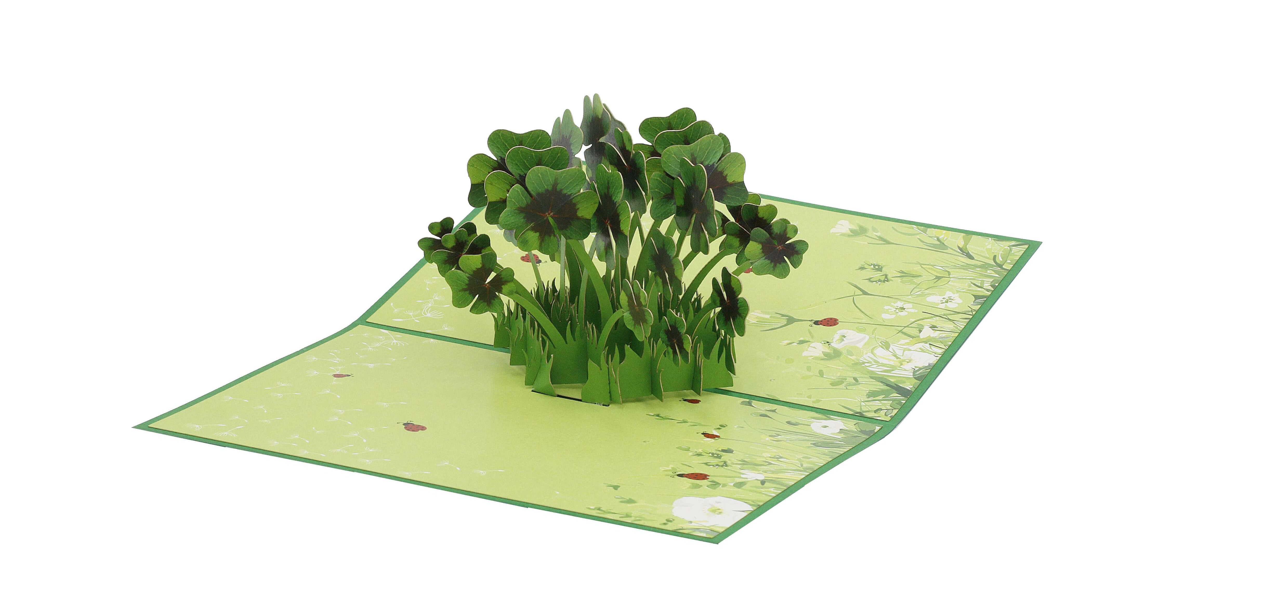 Aufgeklappte grüne Pop-up-Karte mit einem Büschel vierblättriger Kleeblätter auf einer Wiese mit Marienkäfern.