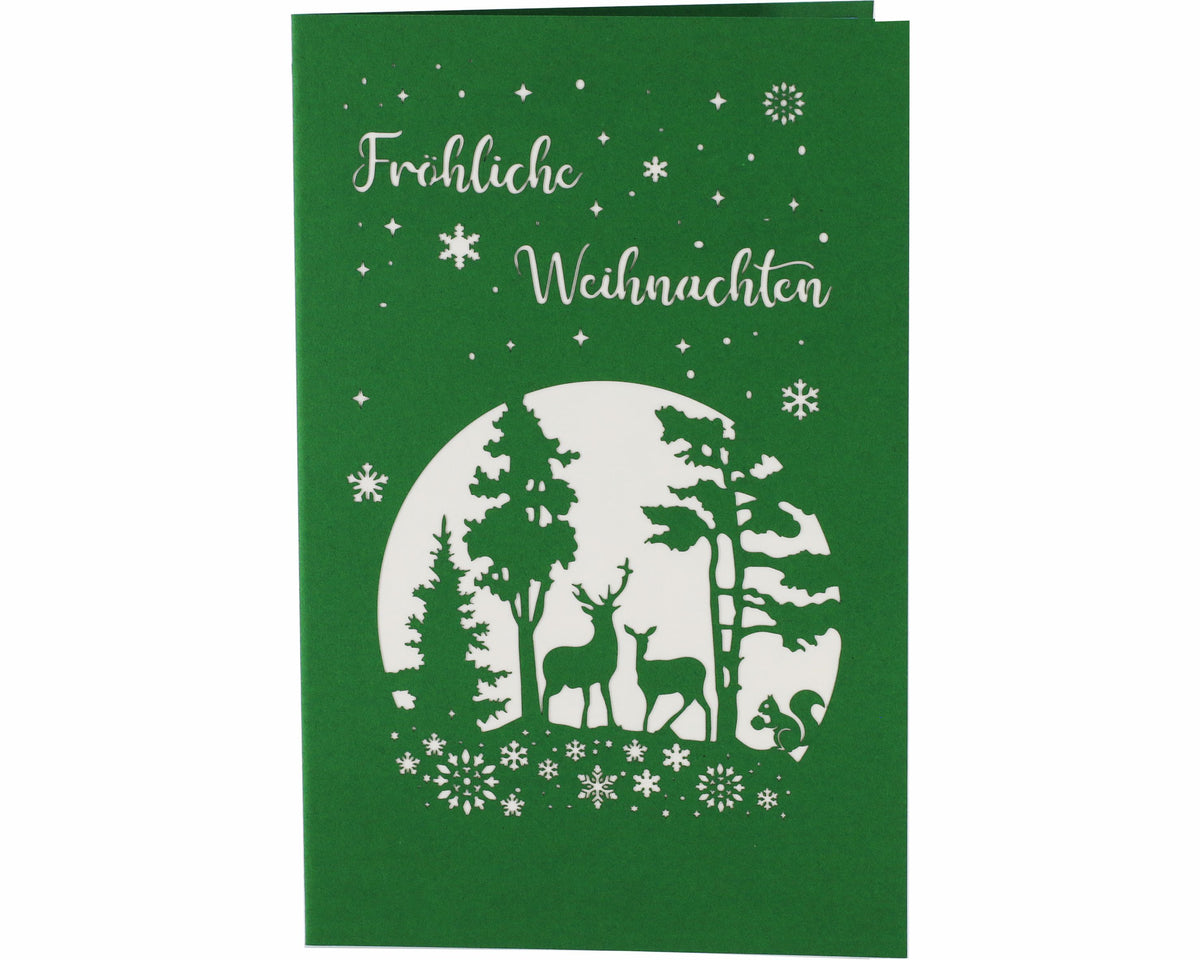 Grüne Vorderseite der Nikolaus Pop-up-Karte mit dem Schriftzug Fröhliche Weihnachten, Sternen, Schneeflocken und einem Winterwald mit Hirsch, Reh und Eichhörnchen als Scherenschnitt.