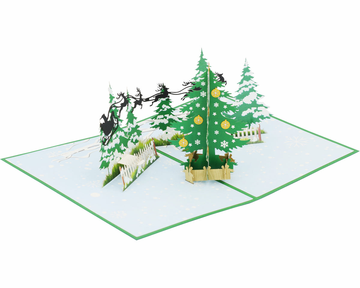 Aufgeklappte Pop-up-Karte mit Winterwald und Rentierschlitten, von schräg oben fotografiert.