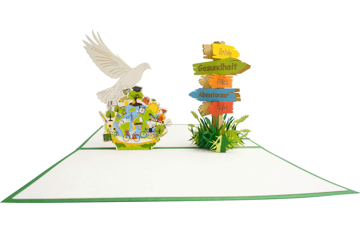 Aufgeklappte Pop-up-Karte mit weißer Friedenstaube über einer bunten Weltkugel, daneben ein Wegweiser mit den Schildern Erfolg, Gesundheit, Glück, Abenteuer und Liebe.