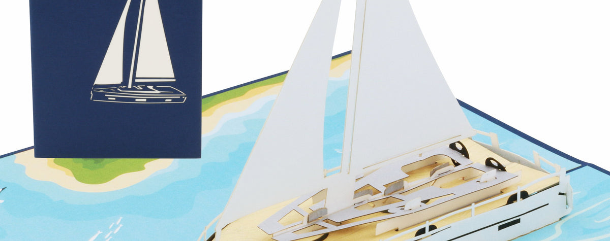 Aufgeklappte Pop-up-Karte mit einer weißen Segelyacht auf blauem Meer, dahinter die blaue Kartenvorderseite mit Segelboot-Scherenschnitt.