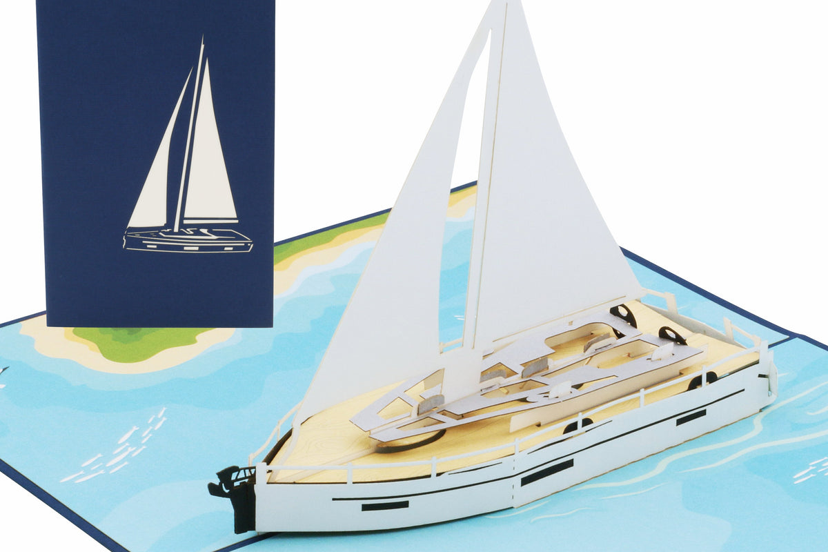 Aufgeklappte Pop-up-Karte mit einer weißen Segelyacht auf blauem Meer, dahinter die blaue Kartenvorderseite mit Segelboot-Scherenschnitt.