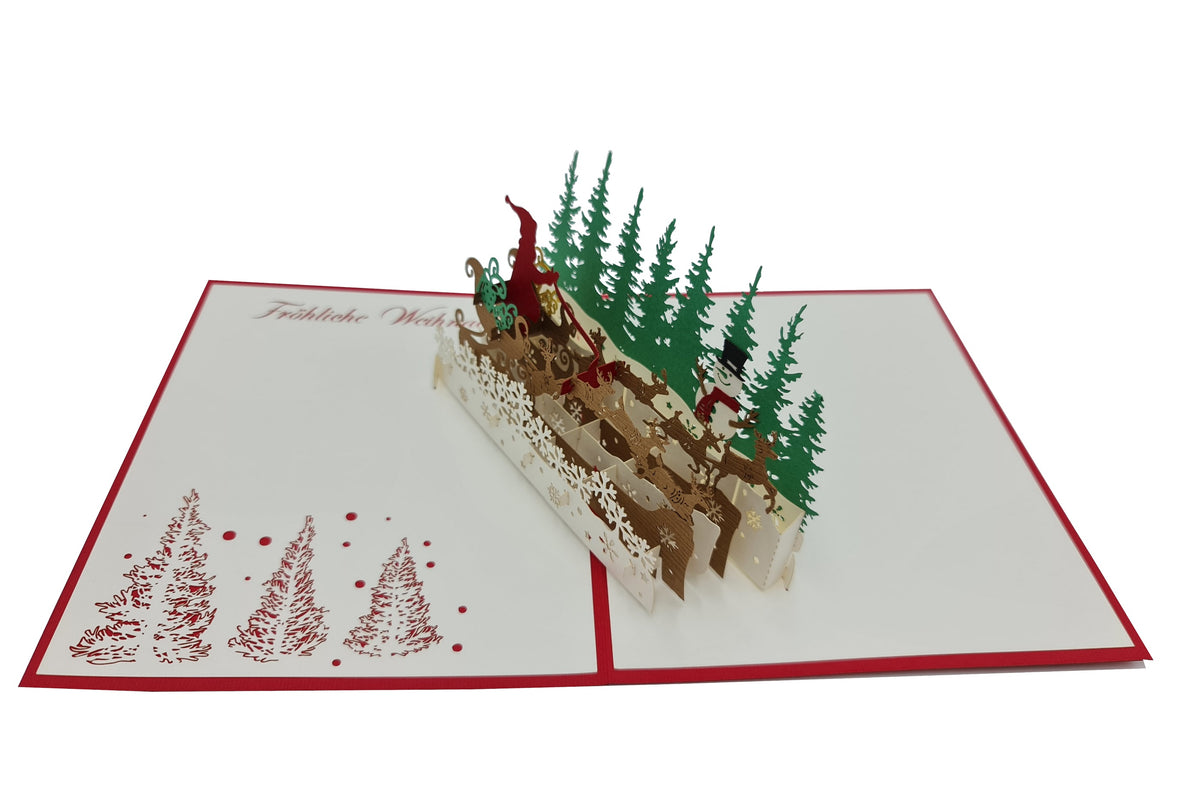 Aufgeklappte Pop-up-Karte mit filigranem Rentierschlitten und grünem Tannenwald, auf der weißen Kartenfläche der Schriftzug Fröhliche Weihnachten und rote Tannenbäume.