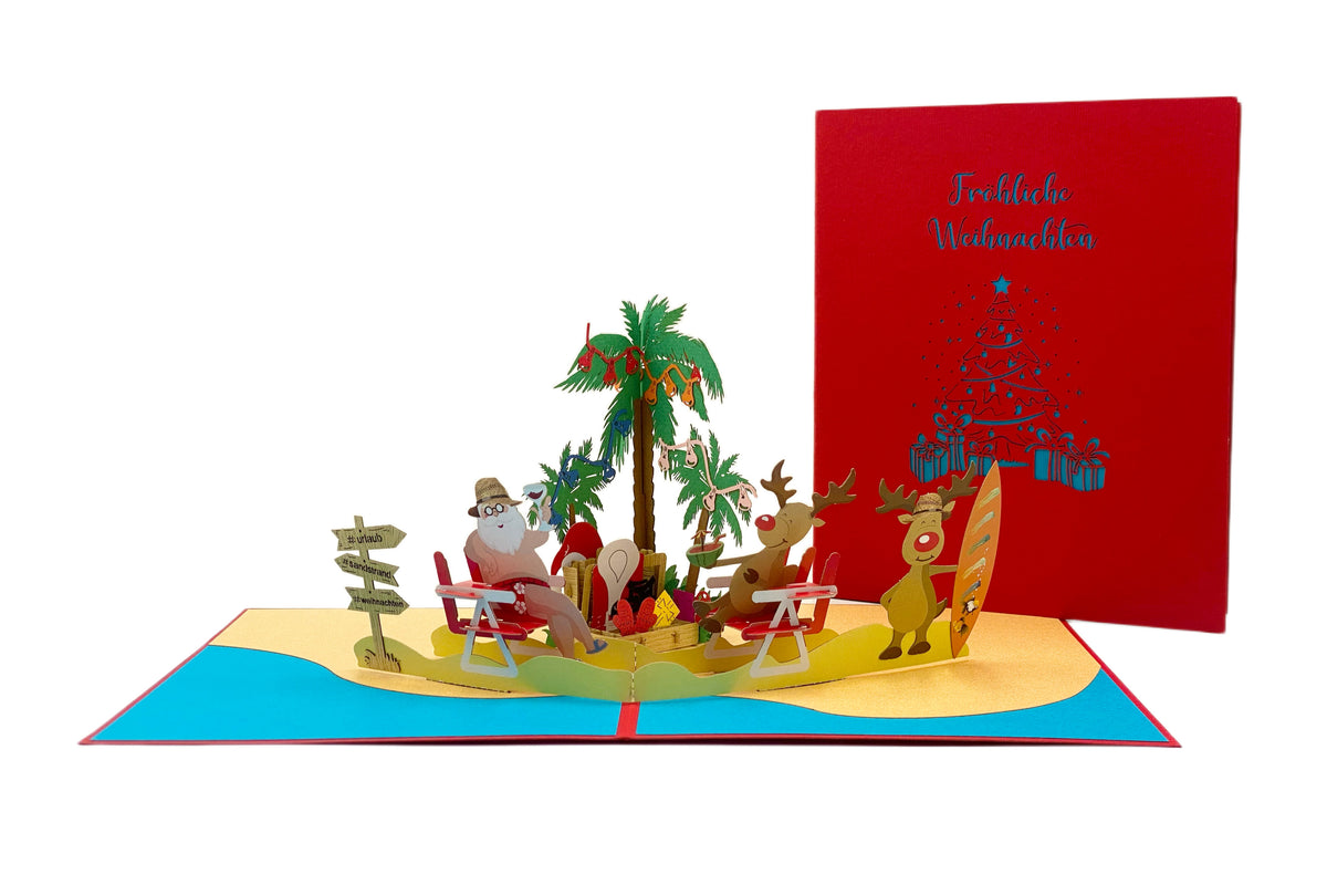 Aufgeklappte Pop-up-Karte mit Weihnachtsmann am Strand, daneben die rote Kartenvorderseite mit dem Schriftzug Fröhliche Weihnachten und einem blauen Weihnachtsbaum aus Geschenken.