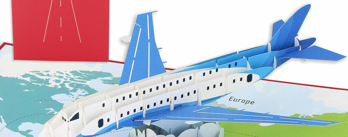 Aufgeklappte Pop-up-Karte mit einem blau-weißen Passagierflugzeug über einer bunten Weltkarte, dahinter die rote Kartenvorderseite mit Flugzeug-Scherenschnitt.