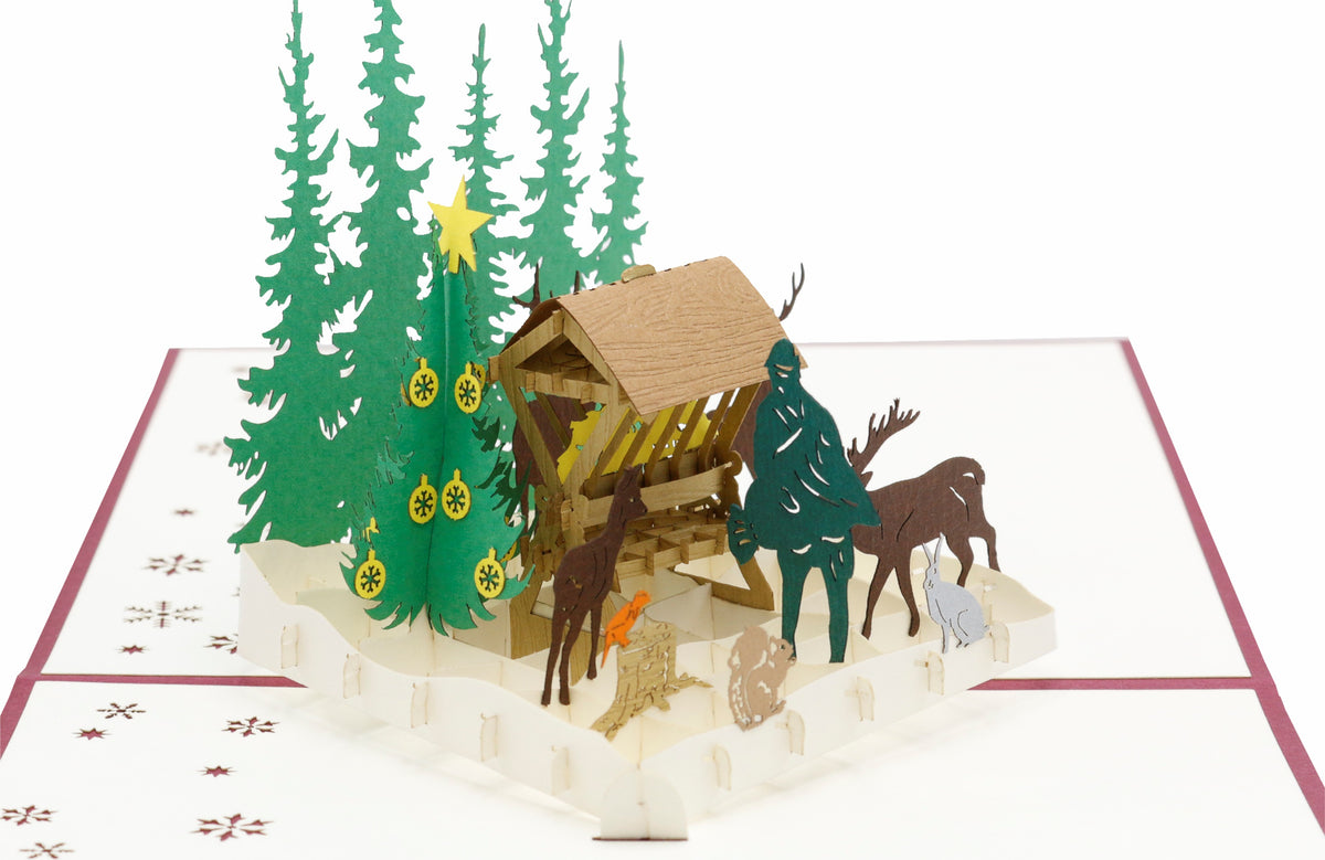 Nahaufnahme der aufgeklappten Pop-up-Karte mit Futterkrippe, Jäger und Waldtieren.