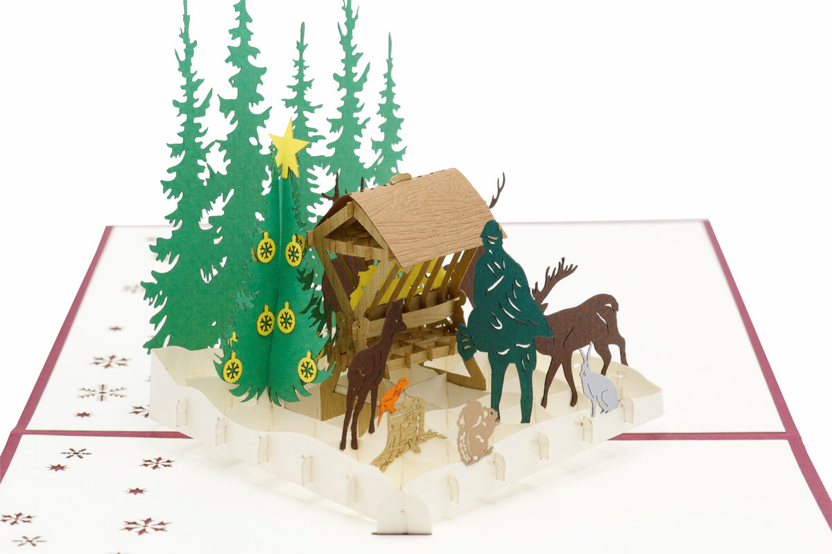 Nahaufnahme der aufgeklappten Pop-up-Karte mit Futterkrippe, Jäger und Waldtieren.