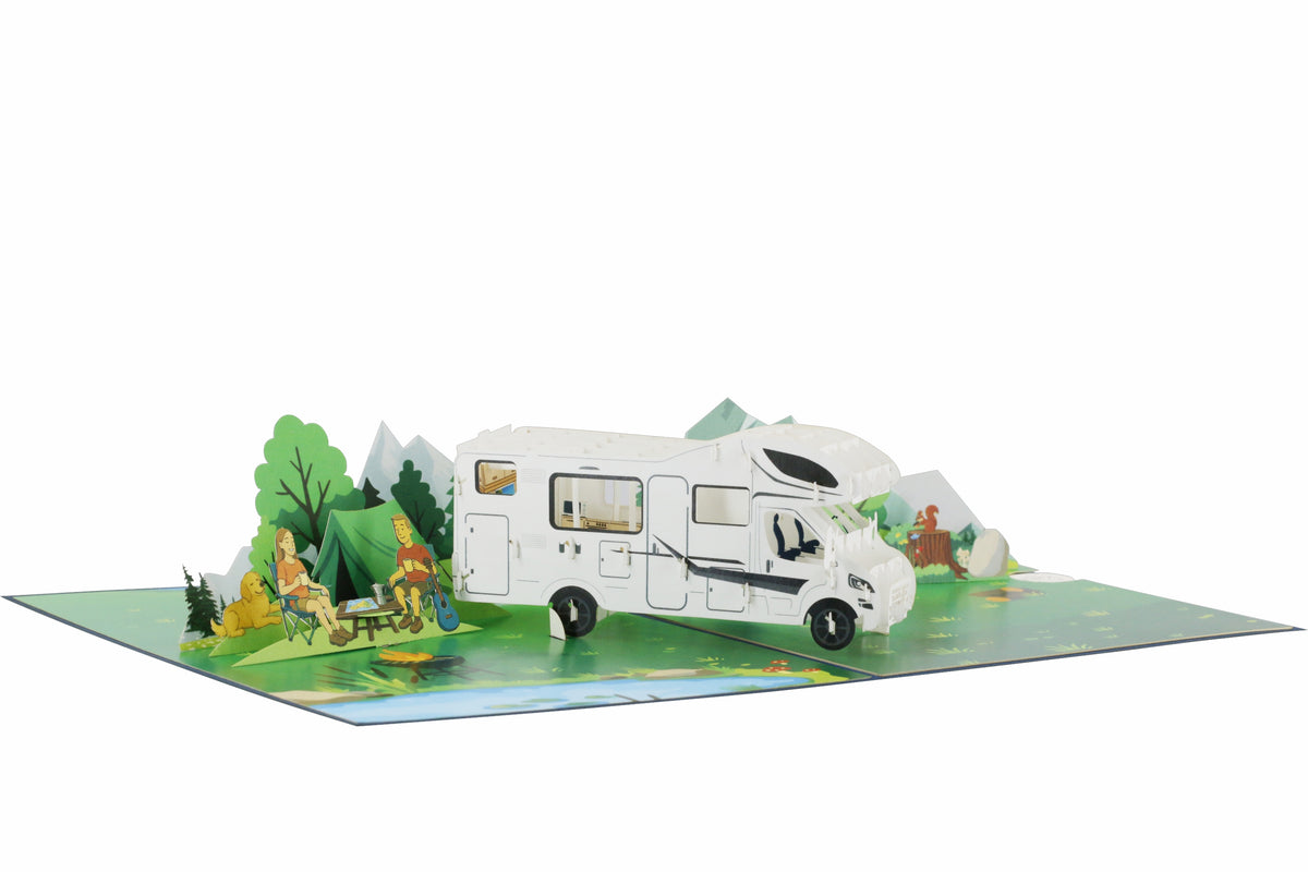 Aufgeklappte Pop-up-Karte mit Wohnmobil, Zelt und Campern vor Bergen, schräg von der Seite fotografiert.