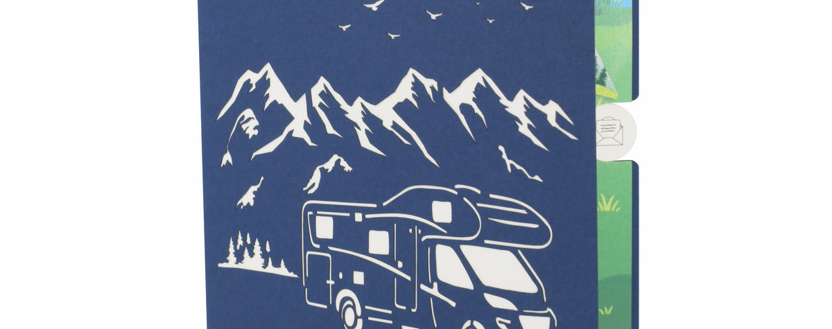blaue karte mit einem wohnmobil als scherenschnitt in der natur vor bergen und vögeln