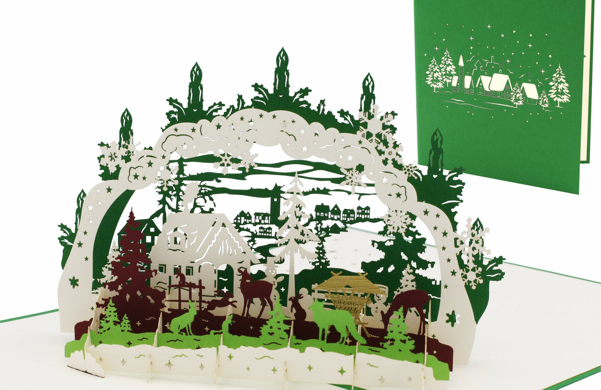 Aufgeklappte Pop-up-Karte mit einem Schwibbogen mit Winterlandschaft, daneben die grüne Kartenvorderseite mit Schwibbogen-Scherenschnitt.