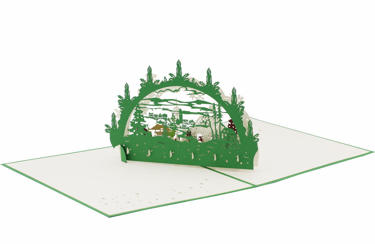 Aufgeklappte Pop-up-Karte mit grünem Schwibbogen und Winterlandschaft, von schräg oben fotografiert.