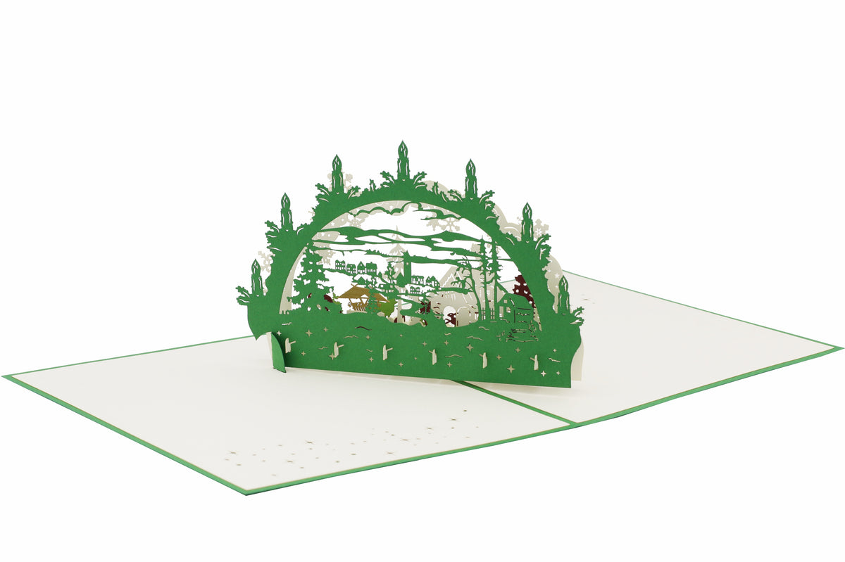 Aufgeklappte Pop-up-Karte mit grünem Schwibbogen und Winterlandschaft, von schräg oben fotografiert.