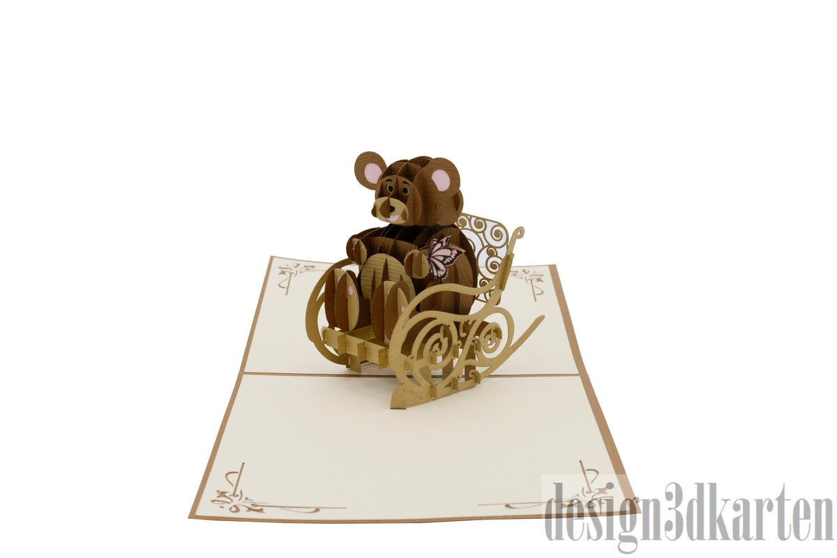 Aufgeklappte Pop-up-Karte mit einem Teddybären im Schaukelstuhl aus Papier.