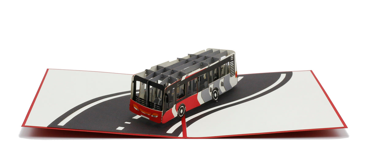 Aufgeklappte Pop-up-Karte mit einem Linienbus auf einer geschwungenen Straße, schräg von oben fotografiert.