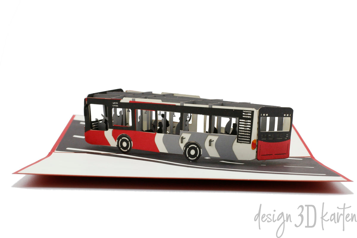 Aufgeklappte Pop-up-Karte mit rot-weißem Bus aus Papier, frontal von der Seite fotografiert.
