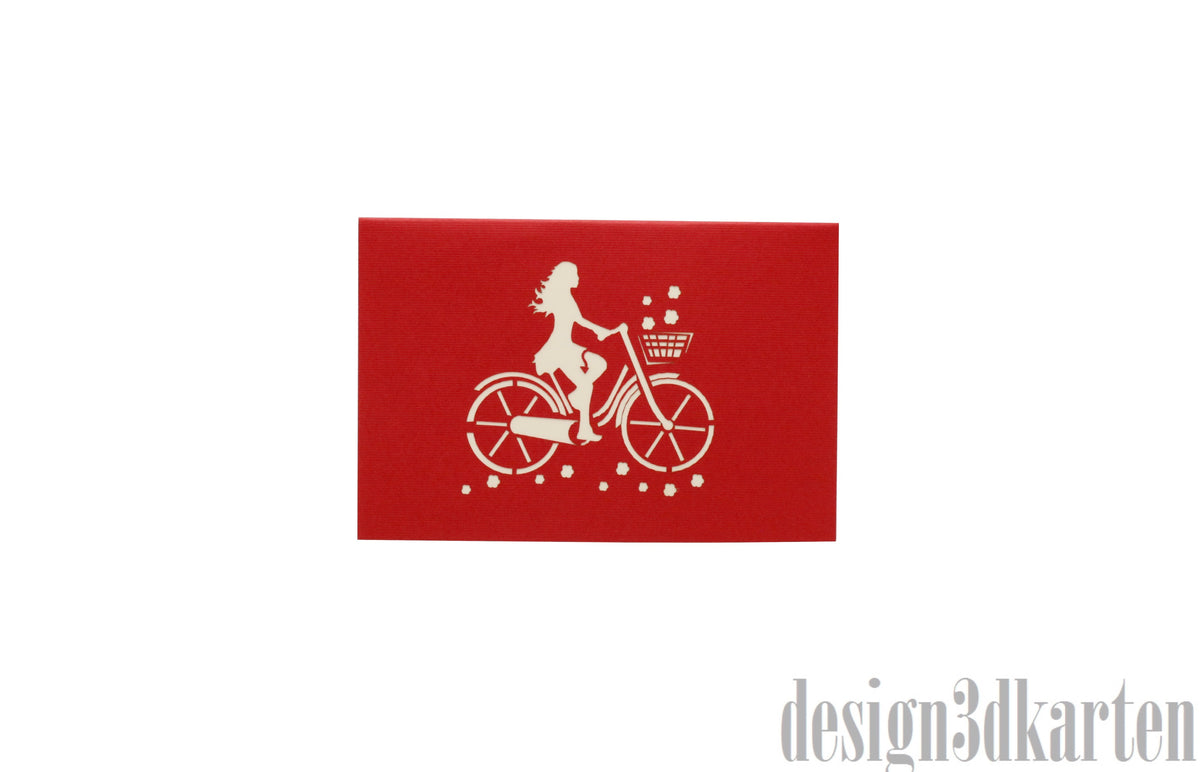 Rote Kartenvorderseite mit einer Radfahrerin auf einem Damenfahrrad als Scherenschnitt.