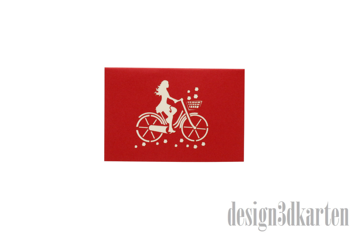 Rote Kartenvorderseite mit einer Radfahrerin auf einem Damenfahrrad als Scherenschnitt.