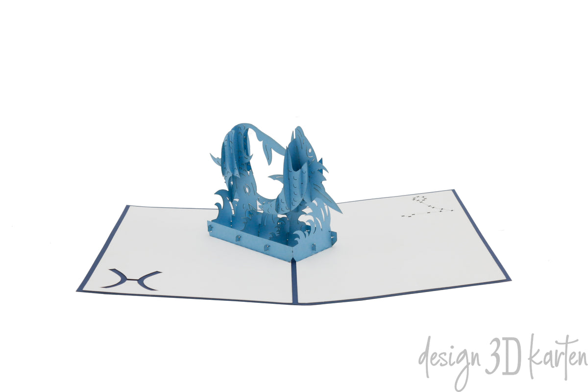 Aufgeklappte Pop-up-Karte mit zwei blauen Fischen, schräg von der Seite fotografiert.