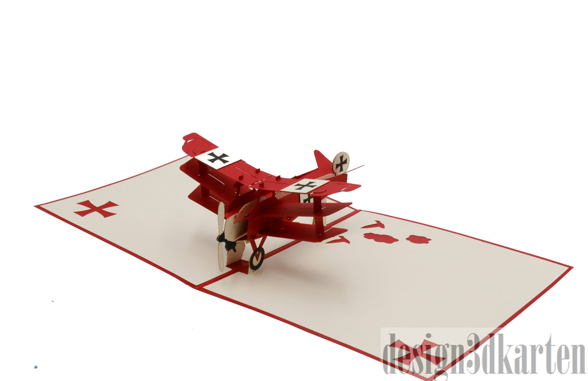 Aufgeklappte Pop-up-Karte mit einem roten Dreidecker-Flugzeug aus Papier, seitlich fotografiert.