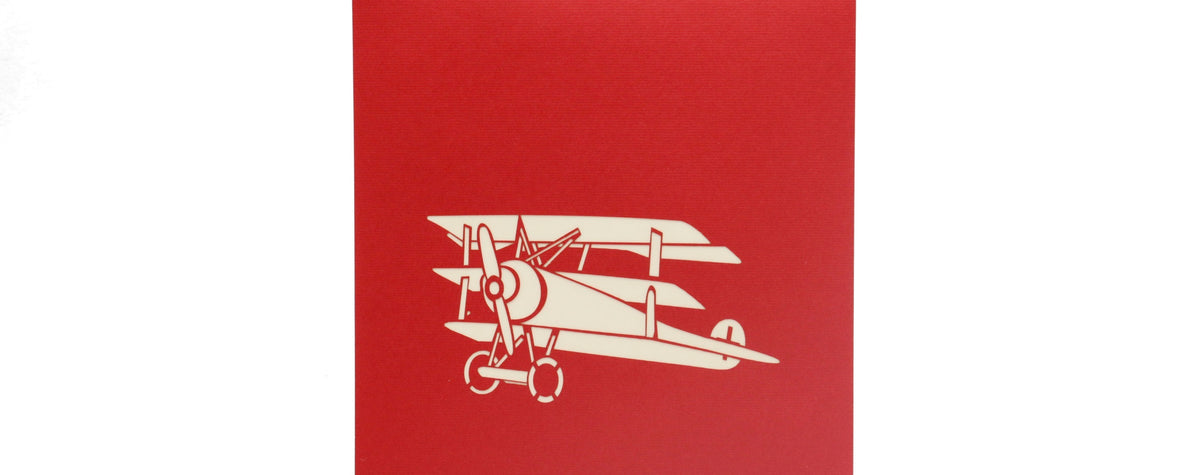 Rote Kartenvorderseite mit einem historischen Doppeldecker-Flugzeug als Scherenschnitt.
