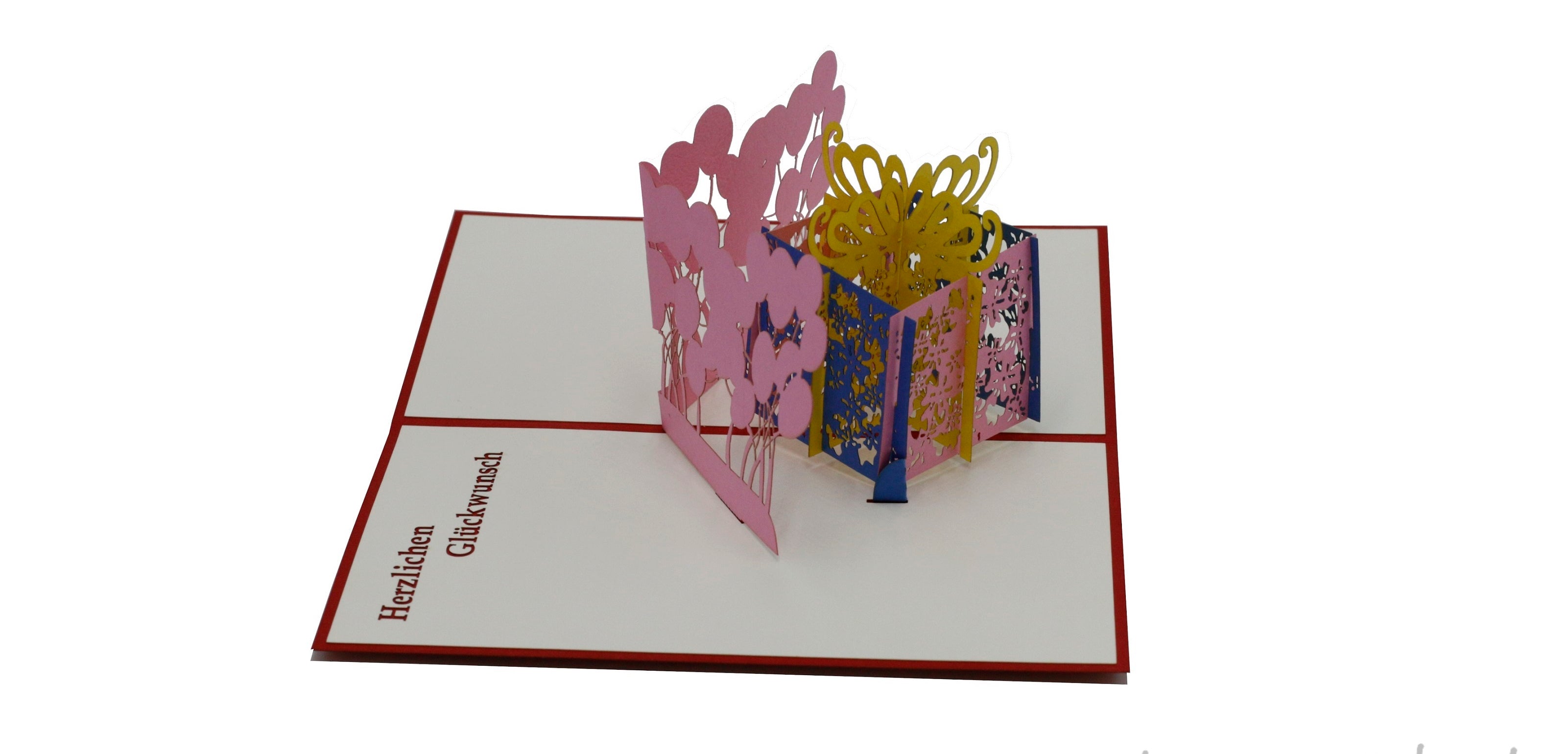Aufgeklappte Pop-up-Karte mit rosa-gelber Geschenkbox und Luftballons, schräg von der Seite fotografiert.