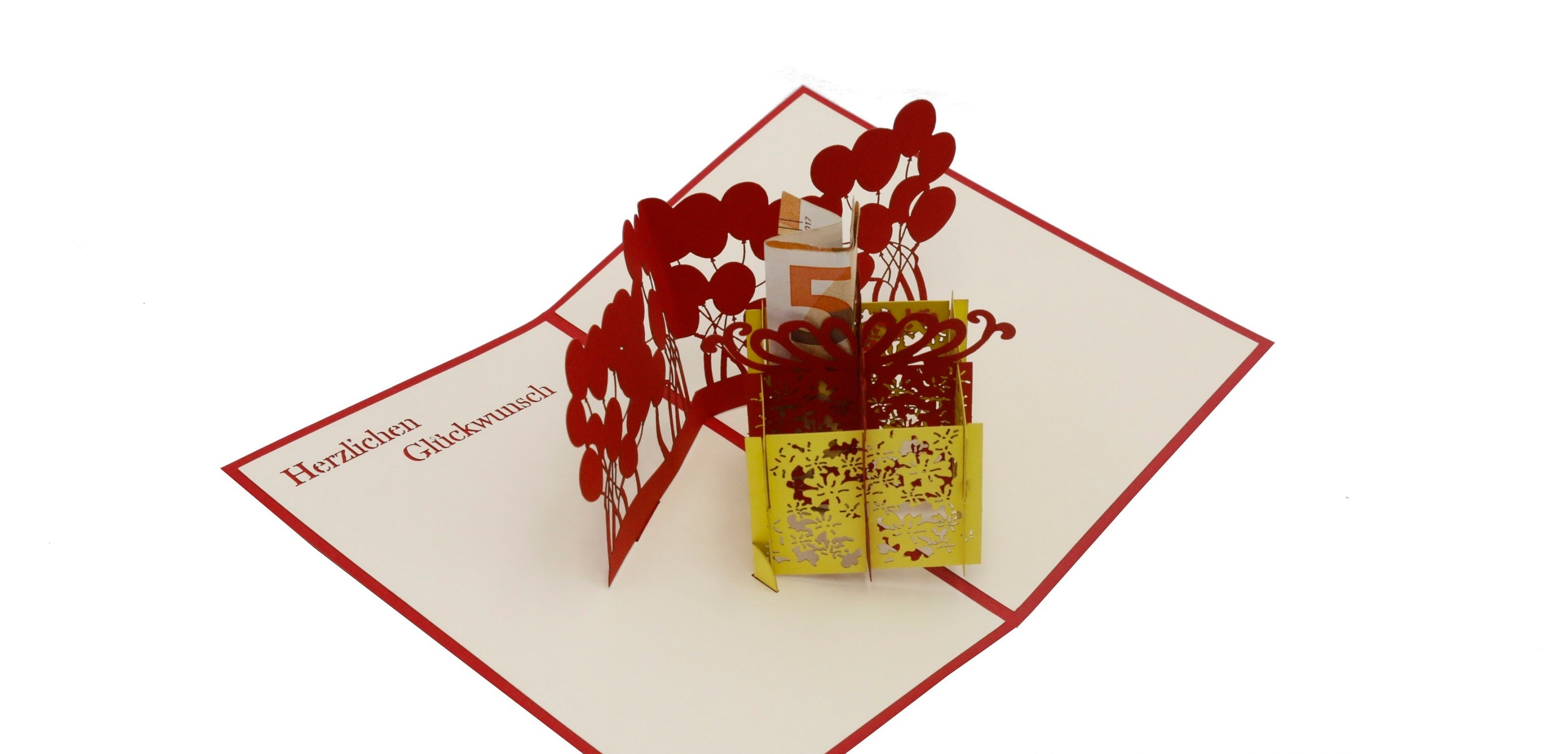 Aufgeklappte Pop-up-Karte mit gelber Geschenkbox und roten Luftballons, schräg von oben fotografiert.