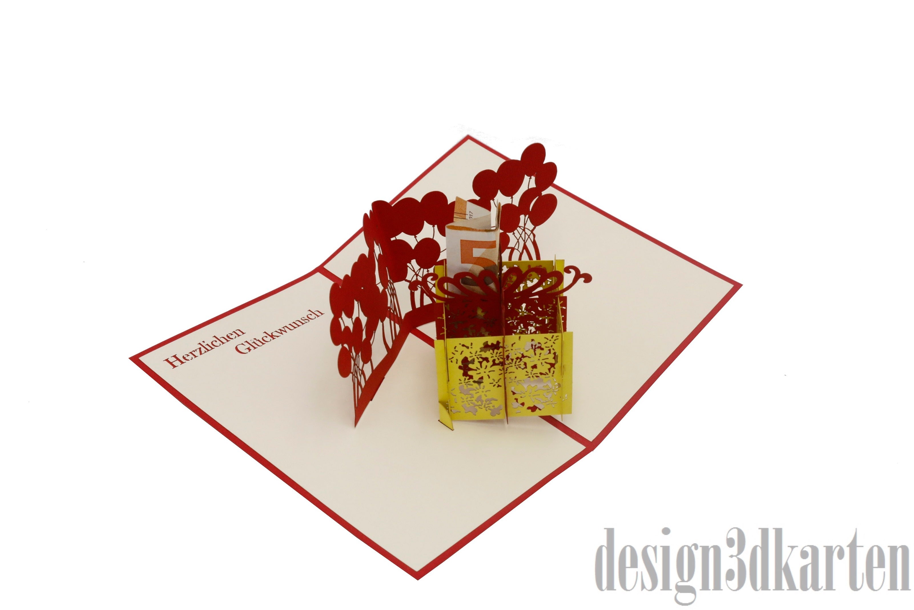 Aufgeklappte Pop-up-Karte mit gelber Geschenkbox und roten Luftballons, schräg von oben fotografiert.