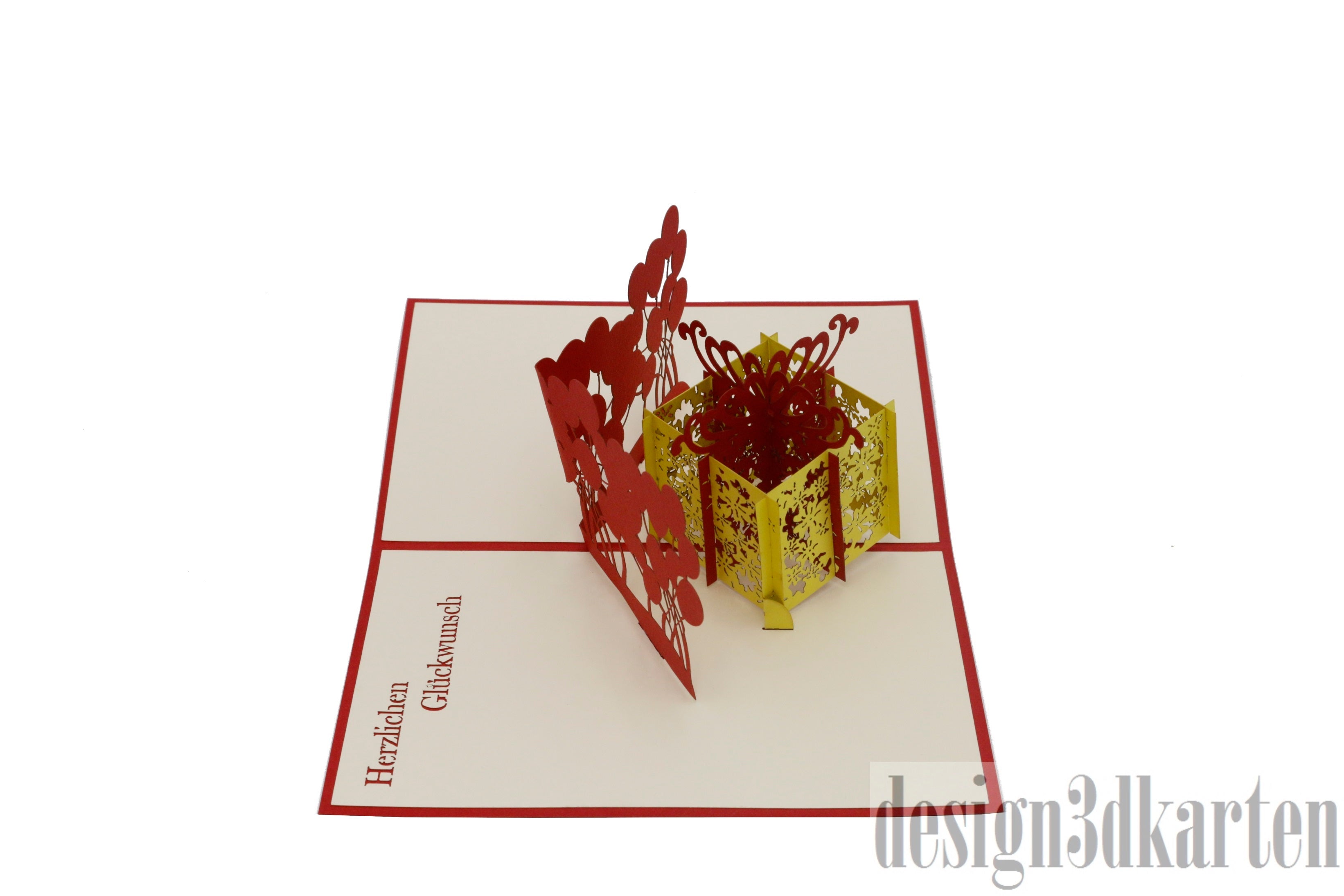Aufgeklappte Pop-up-Karte mit gelber Geschenkbox und Luftballons, seitlich fotografiert.