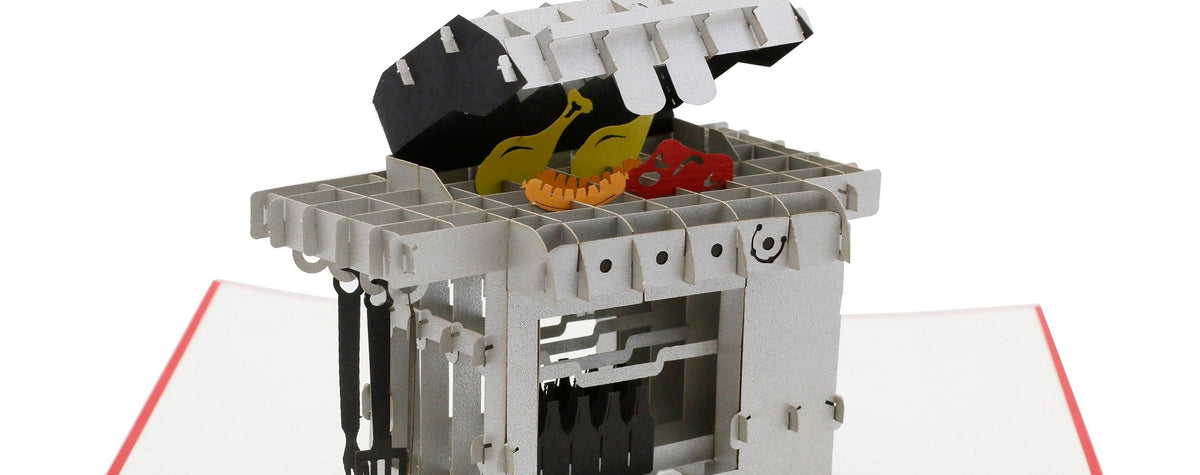 Nahaufnahme der aufgeklappten Pop-up-Karte mit einem Gasgrill aus Papier, auf dem Rost liegen Würstchen und Gemüse.